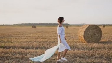 Yan görünümü. Rüzgarda uçan eşarp ile sahada çalışan güzel çekici kadın. Özgürlük kavramı