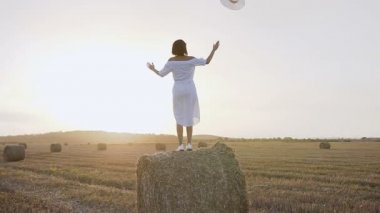 Toskana İtalya dinlenme, samanlık yükselterek üzerinde duran ve silah mavi gökyüzü bulutlu bir arka plan üzerinde düşürücü bir kız. Arkadan görünüm, alanında çekici genç kadın