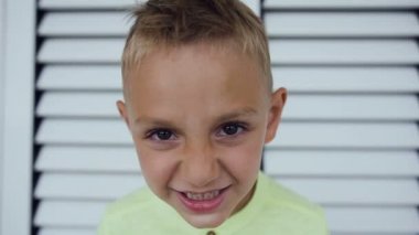 Kızgın 5-6 yaş çocuk portresi kadar beyaz kapılar arka plan üzerinde kapatın. Kameraya bakıyor küçük çocuk kızgın komik surat. Çocuk portre, ciddi ve kızgın çocuk kameraya bakıyor