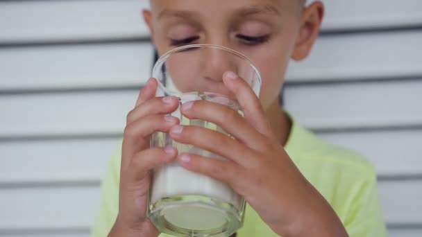 O bonitinho bebe leite de manhã. Criança branca bonito beber leite de um copo. Menino bebe leite — Vídeo de Stock