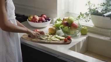 Eller elma dilimleri bir meyve salatası için kahvaltı için mutfakta sabah kesti. Meyve salatası hazırlanması. Sağlıklı beslenme