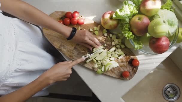 Üstten görünüm. Genç kadın elma güler yüzlü için hazır olun. Bilinçli ve sağlıklı kız kesme elma bir vejetaryen yemek için. Karışık salata hazırlamak için meyve ve sebze Dilimleme bir kız — Stok video