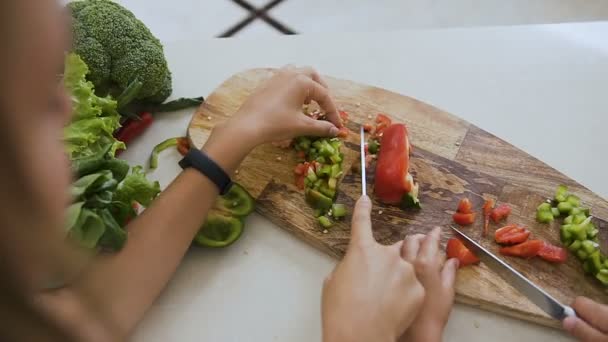 Zbliżenie dłoni dziewczyny nastolatki za pomocą nóż kuchenny, ucząc się wyciąć warzywo zielony pieprz przygotowanie żywności w domu w kuchni. Dwie siostry Dowiedz się warzywa krojone nożem — Wideo stockowe