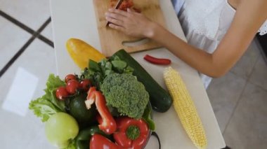 Üstten görünüm. İki kız kardeş bir ahşap tahta üzerinde biber biber ve avokado salata mutfak masasında yemek pişirmek için kesti. Kesme biber ve avokado
