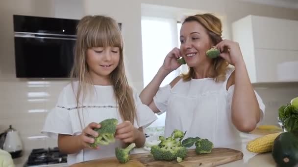 Mamma med sin dotter ha kul i köket med hälsosam mat. Glad rolig mamma med dotter matlagning grönsaker och spelar i köket hemma — Stockvideo
