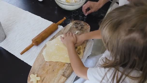 W górnej części widoku. Dziewczynka z długimi włosami w białej sukni sprawia, że ciasto na pierniki w domowej kuchni. Dziewczynka jest do pieczenia ciasteczek dla rodziny — Wideo stockowe