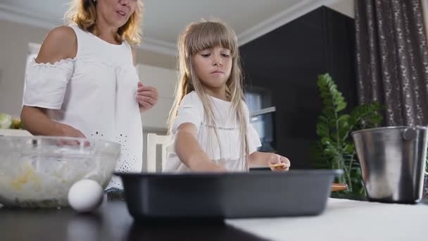 Giovane madre e piccola figlia che fanno biscotti in cucina. Donna e bambina in cucina mettendo l'impasto dei biscotti sulla teglia — Video Stock