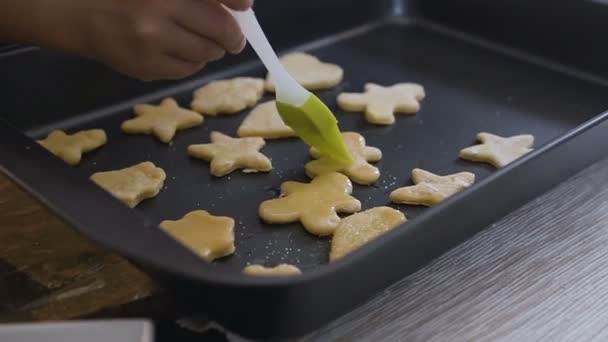 Close-up of a woman hand placing cookie dough on baking tray. Raw shape cookies with sugar icing on baking tray — Stock Video
