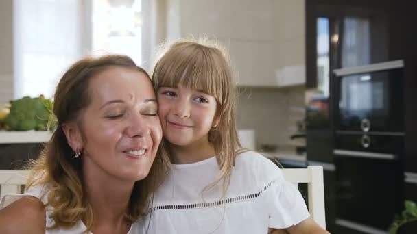 Porträt einer jungen Mutter und ihrer Tochter im Haus. Nahaufnahme Porträt von glücklichen Mutter und Tochter lächeln fröhlich umarmen — Stockvideo