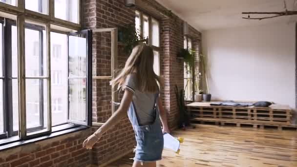 满足白种人时髦的女孩与耳机周围的脖子是步行与极大的乐趣后成功乘坐滑板在室内附近的砖墙 — 图库视频影像