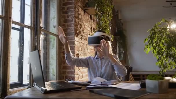 Joven mujer de negocios con auriculares de realidad virtual en la oficina. En una chica de la clase de ciencias de la computación con auriculares de realidad virtual trabaja en un proyecto de programación en el interior. Hermosa chica jugando — Vídeo de stock