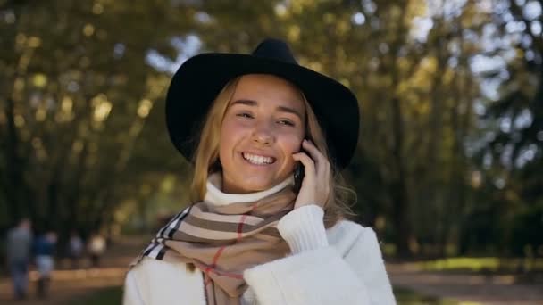 Retrato de una hermosa mujer tomando café y hablando con alguien en su teléfono inteligente durante una caminata por el parque . — Vídeo de stock