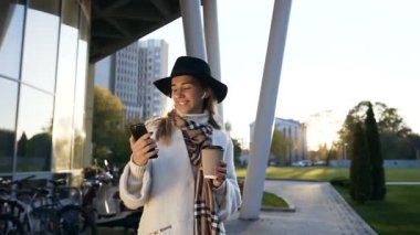 Kahve içme ve akıllı telefonda sohbet kulaklık ile şapkalı güzel kadın.