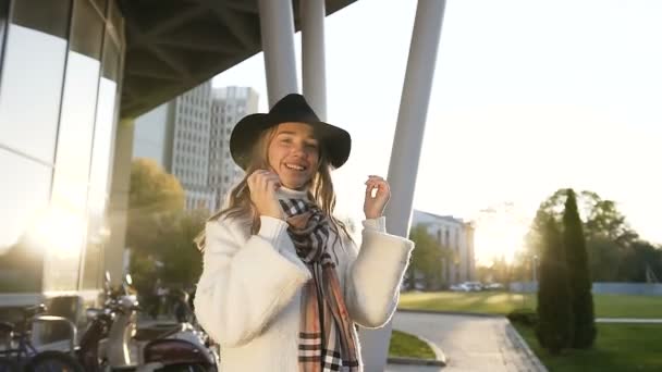 Stylish blonde hair girl spining and possing on the camera on the modern building background. — Stock Video