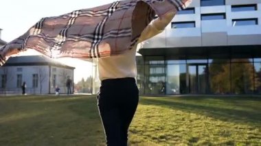Mutlu şık kız ile eşarp gündoğumu sırasında modern bina arka plan üzerinde çalışan.