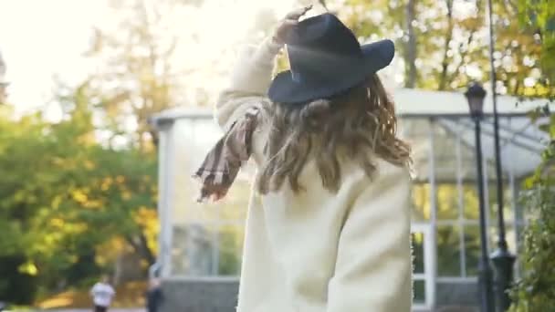 Stylishe chica feliz caminando en el parque de la ciudad, girando a la cámara y sonreír . — Vídeo de stock