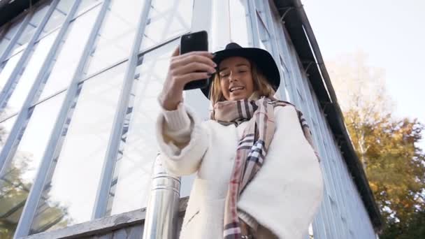 Hermosa chica en el sombrero possing en el teléfono inteligente en el parque . — Vídeo de stock