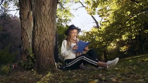 Κομψό ξανθιά μαλλιά γυναίκα χαλαρώνοντας στο πάρκο και την ανάγνωση του βιβλίου. — Αρχείο Βίντεο