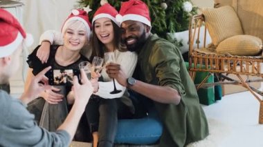 arka görüş. Bir çocuk fotoğrafı sarılmak ve bir Noel ağacı arka plan üzerinde beyaz şarap içmek arkadaş olun. Yeni yıl içinde neşeli şirketin elbise çok fotoğrafı çekilen calebrate yeni yıl