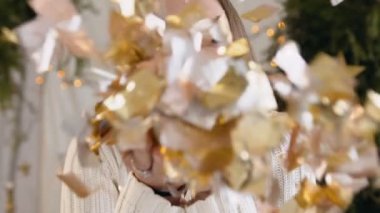 Yakın çekim. Altın glitter üfleme güzel ve genç birbayan. Sevimli kız pozlar kamera, arka plan Noel süslemeleri gülümsüyor. Yeni yıl. Noel kutlaması