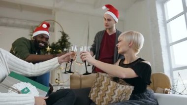 Neşeli arkadaşları sahip kutlamak Noel ve yeni yıl, rahat daire, Noel ağacı önce kanepede siitting süre tost içme. Karışık yarış grup ile yılbaşı partisinde genç insan