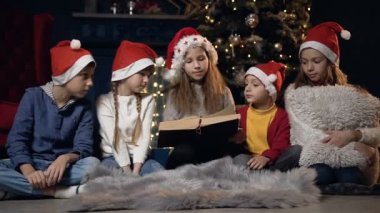 Güzel çocuklar Noel ağacı yakınındaki kitap oturma okuma.
