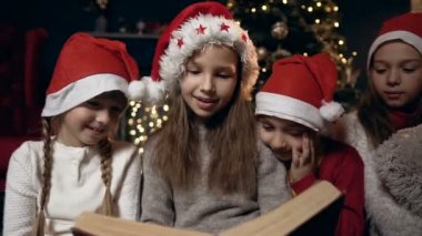 Portre çekim güzel çocuk Noel ağacının yanında oturan kitap okuma.