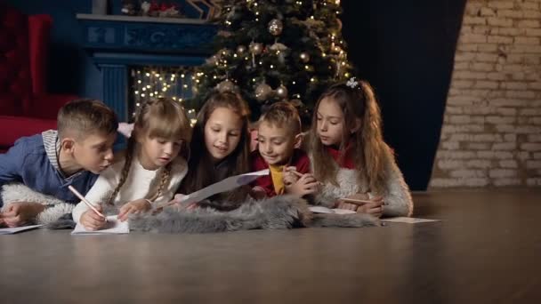 Cinq enfants élégants écrivent quelque chose sur le papier tout en se relaxant dans la chambre . — Video