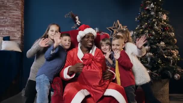 African man in santa claus costume and cute kids waving to the camera. — Αρχείο Βίντεο