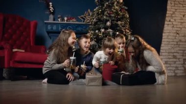 Yere rahatlatıcı ve Noel ağacı arka plan üzerinde çay içme mutlu sevimli çocuklar.