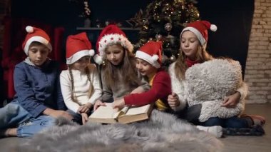 Şirin çocuk Noel dekorasyonu ile odasında kitap okurken sayfaları çevirme.