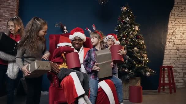 Bonito crianças gostando dos presentes recebendo de Papai Noel no fundo da árvore de natal . — Vídeo de Stock