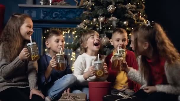 Boldog szép gyerek teát iszik, és nevetve a hangulatos karácsonyi szobában. — Stock videók