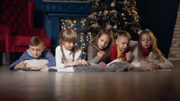 Niños guapos tirados en el suelo mientras dibujan algo en el papel . — Vídeos de Stock