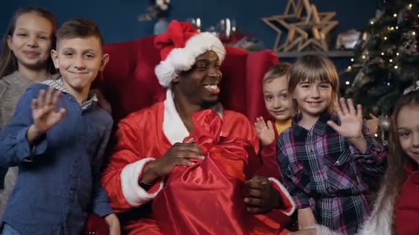 Close up tiro de Papai Noel e crianças bonitos acenando para a câmera . — Vídeo de Stock