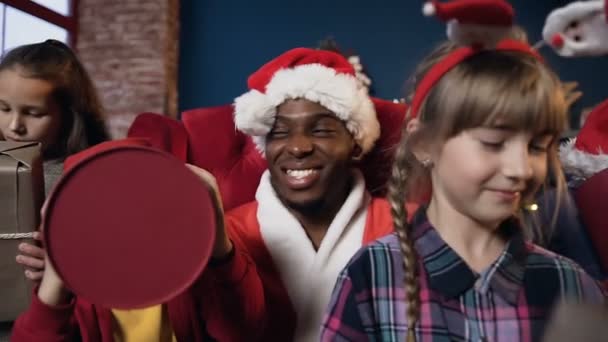 Portrait shot of little children joying the gifts getting from Santa Claus on the christmas tree background. — Stock Video