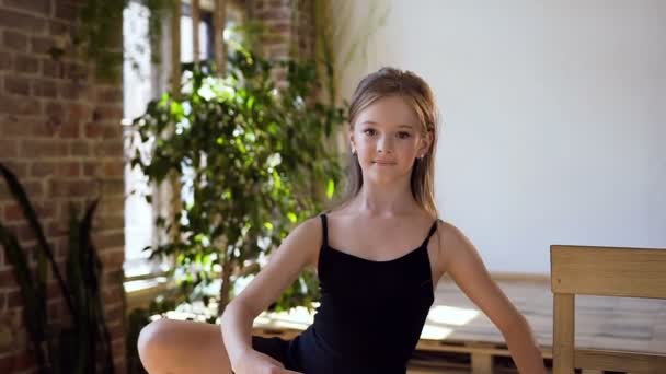 Okouzlující dívka v černém tutu provádí prvek klasického baletu cvičení v tanečním sále. Mladá krásná baletka v černém tutu dělá strečink a zahřívání cvičení — Stock video