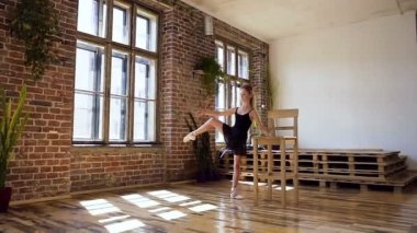 Siyah elbiseli zarif bir genç Balerin Bale öğeleri modern balo salonu dans ediyor. Güzel kız klasik bale egzersiz unsuru gerçekleştirir