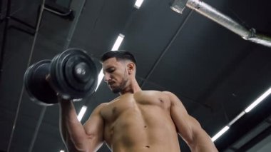 Spor eğitim sırasında dumbbells ile eller için egzersizler yapma adam konsantre.