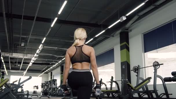 Женщина делает шаги с гантелями во время тренировки в спортзале . — стоковое видео