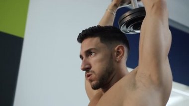 Çıplak gövde egzersizleri dumbbell ile eller için yapım ile kendine güvenen genç adam portresi.