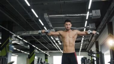Güzel spor adam ile nake gövde egzersizleri dumbbells ile eller için yapıyor.