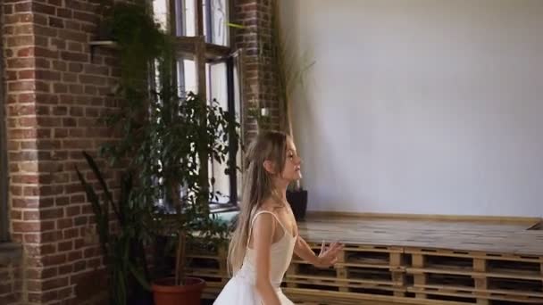 Professionelle Balletttänzerin in weißem Tutu führt klassischen Balletttanz auf, sie trainiert anmutig in Spitzenballettschuhen. Anmutige charmante Ballerina übt Ballettbewegungen im Tanzsaal
