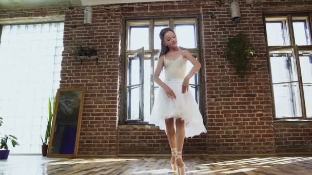 La joven bailarina en tutú blanco y zapatos de ballet está practicando movimientos de baile. Joven bailarina en vestido de ballet en la escuela de baile — Vídeos de Stock