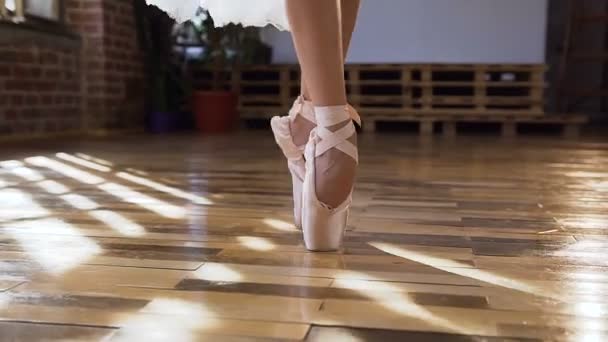 Detail baletka elegantní nohy v baletní střevíčky tančí baletní prvky na dřevěnou podlahu v baletu. Tančící baletky nohy v tanečním sále