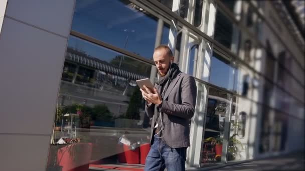 Hombre de negocios guapo trabajando en una tableta durante el almuerzo cerca del centro de oficinas. Al aire libre. Concepto: tecnología, viajes de negocios, negocios, Wall Street — Vídeo de stock