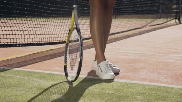 Close-up shot van vrouwelijke speler draaiend tennisracket op de grond. — Stockvideo