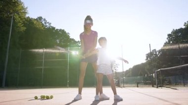 Küçük kız tenis oynamaya öğretim çekici kadın koç.