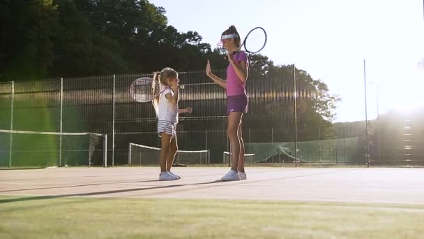 Lilla tennisspelare ger fem till söt kvinnlig tränare och kramas efter tennis träning på banan. — Stockvideo