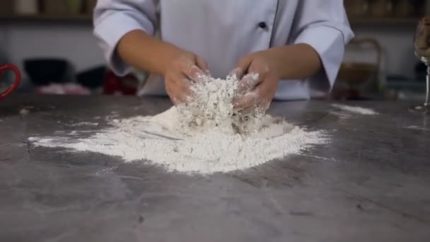 Pâte à pétrir confiseur tout en mélangeant l'eau avec de la farine sur la table . — Video